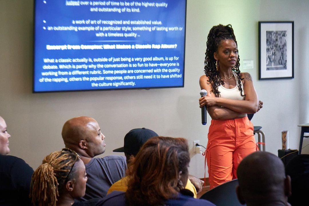 Dynasty speaking with a seated audience during a creative residency